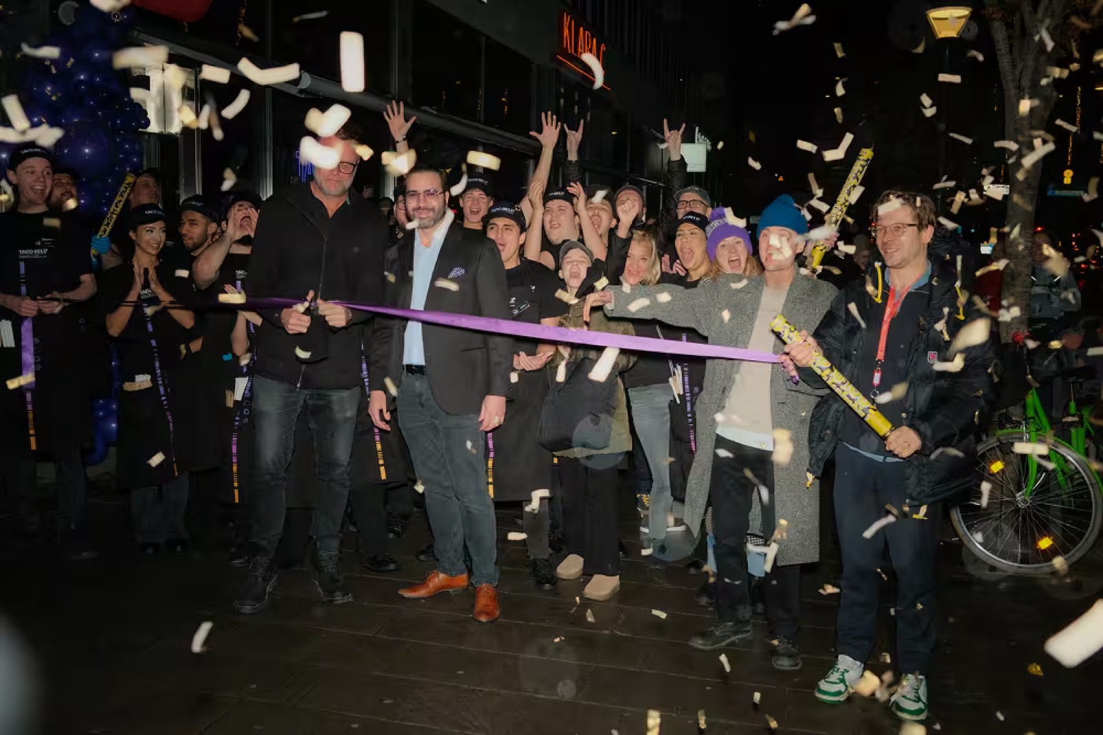 The ribbon being cut outside the restaurant with the crew lined up behind it.
